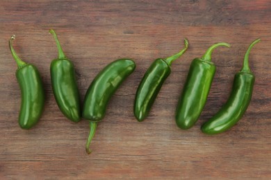 Photo of Fresh green jalapeno peppers on wooden table, flat lay