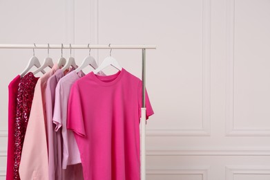 Photo of Rack with different stylish women`s clothes near white wall, space for text