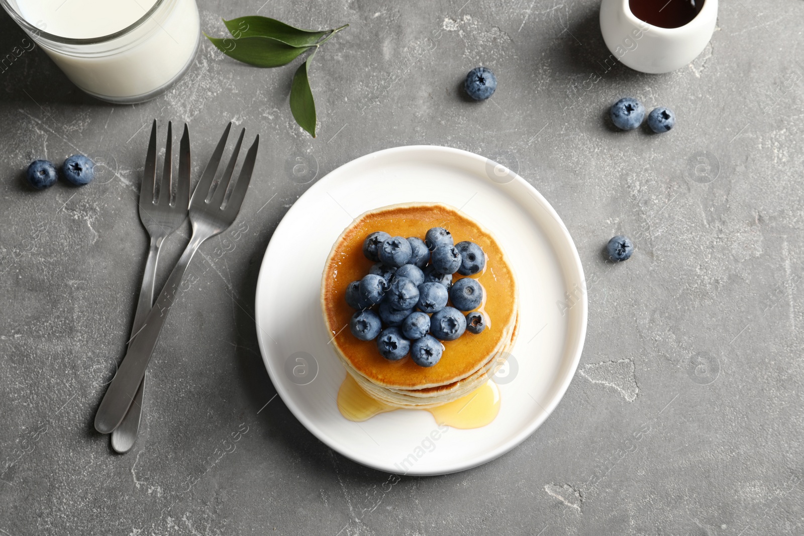 Photo of Plate with pancakes and berries on grey background, top view