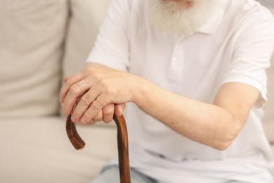Photo of Senior man with walking cane on sofa, closeup