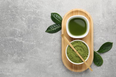 Photo of Green matcha powder, bamboo scoop, fresh beverage and leaves on light grey table, flat lay. Space for text