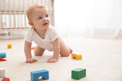 Photo of Cute little baby crawling on carpet indoors, space for text