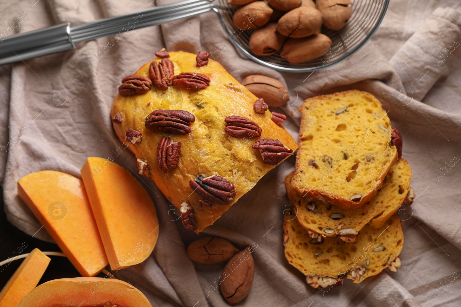 Photo of Delicious pumpkin bread with pecan nuts on tablecloth, flat lay