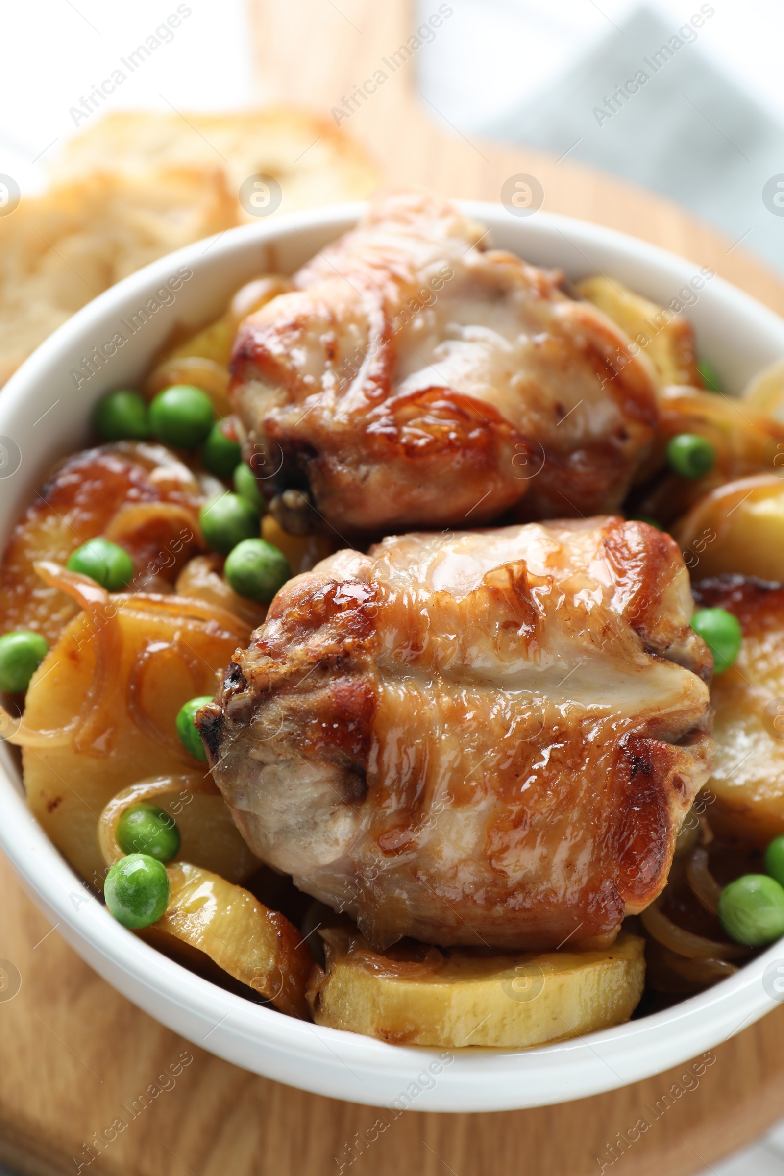 Photo of Tasty cooked rabbit with vegetables in bowl on wooden board, closeup