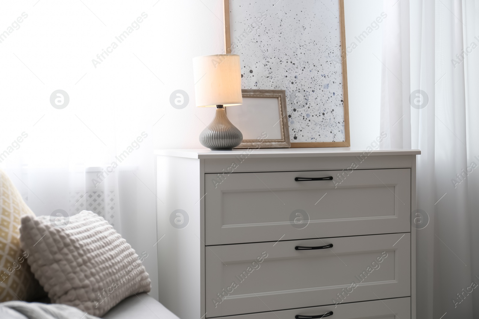 Photo of Modern stylish chest of drawers near window in living room. Interior design