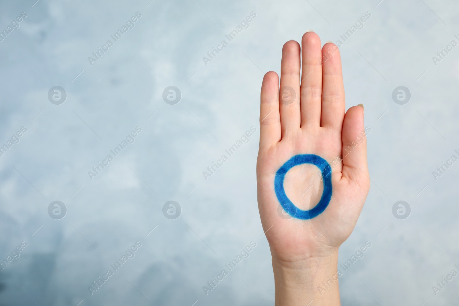 Photo of Woman showing blue circle drawn on palm against color background, closeup. World Diabetes Day