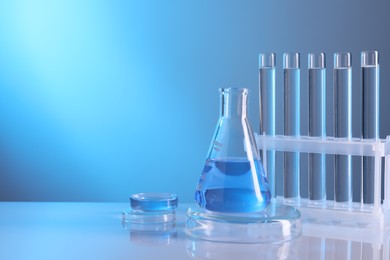 Photo of Laboratory analysis. Different glassware on table against light blue background, space for text
