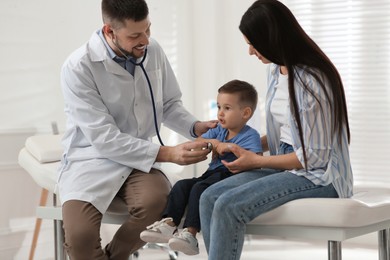 Mother and son visiting pediatrician in hospital. Doctor examining little boy