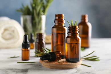 Bottles with rosemary essential oil on table