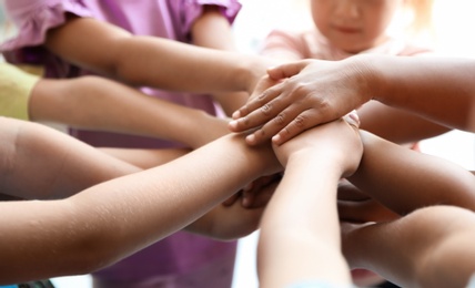 Photo of Little children putting their hands together, closeup. Unity concept