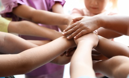 Little children putting their hands together, closeup. Unity concept