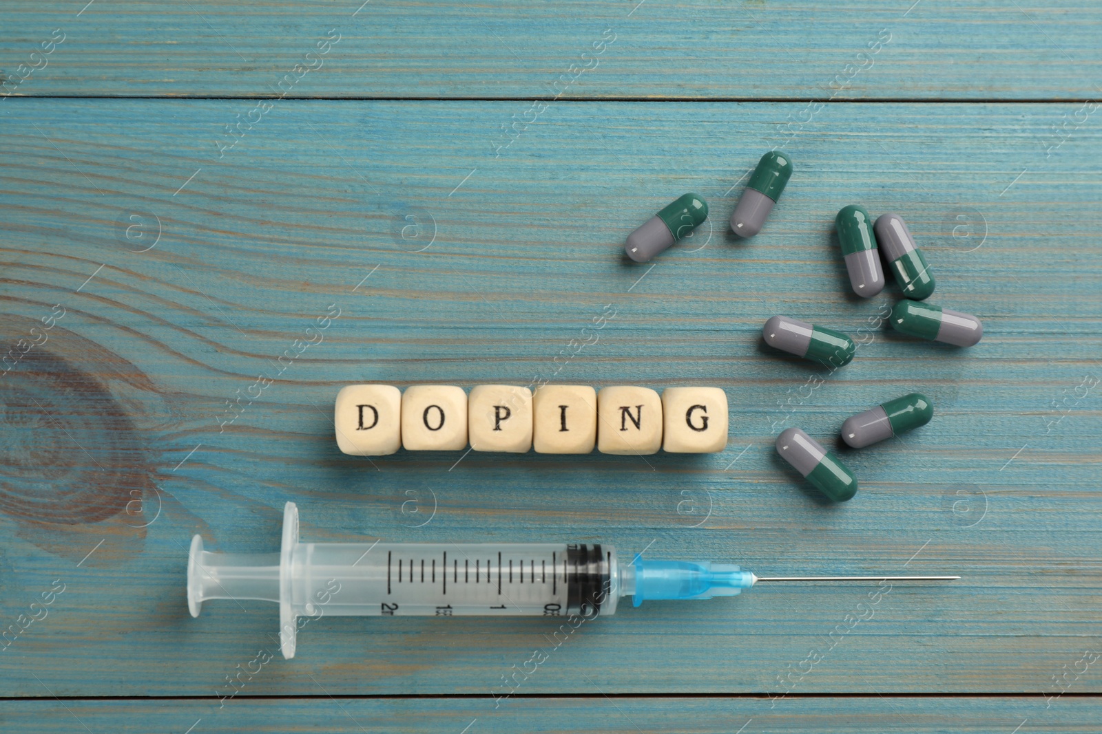 Photo of Cubes with word Doping and drugs on light blue wooden background, flat lay