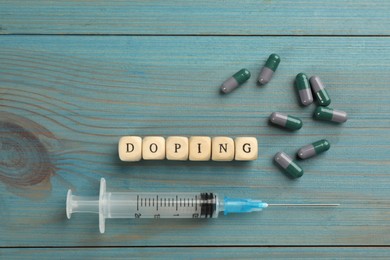 Cubes with word Doping and drugs on light blue wooden background, flat lay