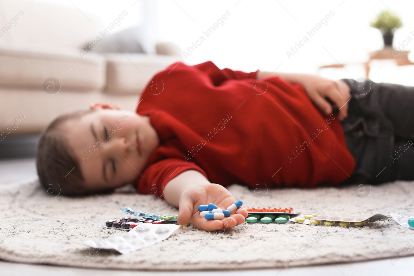 Photo of Unconscious little child with pills lying on floor at home. Household danger