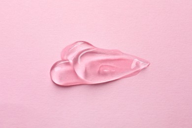 Photo of Swatches of cosmetic gel on pink background, top view