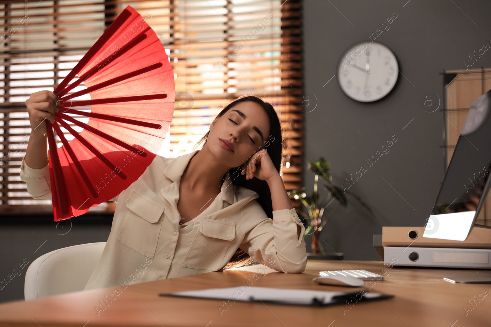 Photo of Woman with hand fan suffering from heat at home. Summer season