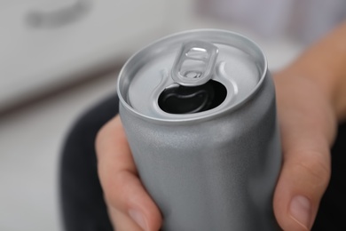 Photo of Man holding open aluminum can on blurred background, closeup. Space for design