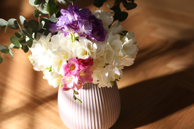 Beautiful bouquet with spring freesia flowers on sunlit wooden table in room, closeup