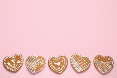 Photo of Gingerbread hearts decorated with icing on pink background, flat lay. Space for text