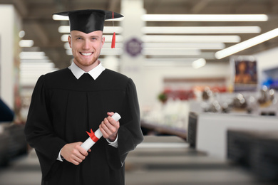Happy student with graduation hat and diploma indoors, space for text