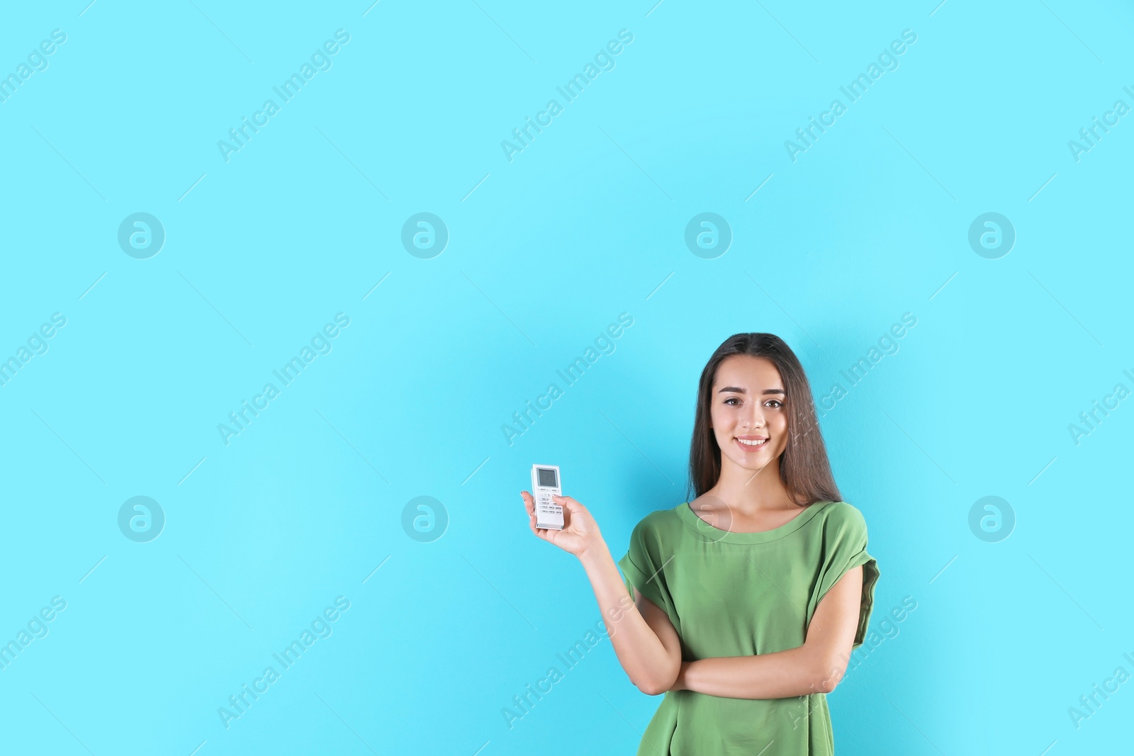 Photo of Young woman switching on air conditioner on color background