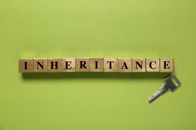 Photo of Word Inheritance made with cubes and key on light green background, flat lay