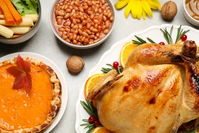 Traditional Thanksgiving day feast with delicious cooked turkey and other seasonal dishes served on grey table, flat lay