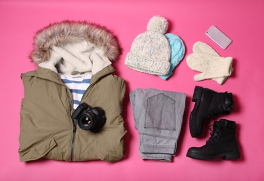 Flat lay composition with warm clothes for winter vacation on color background