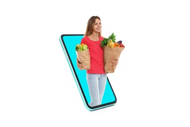 Image of Grocery shopping via internet. Happy woman with bags full of products walking out of huge smartphone on white background