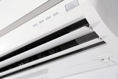 Modern air conditioner on white wall indoors, closeup view