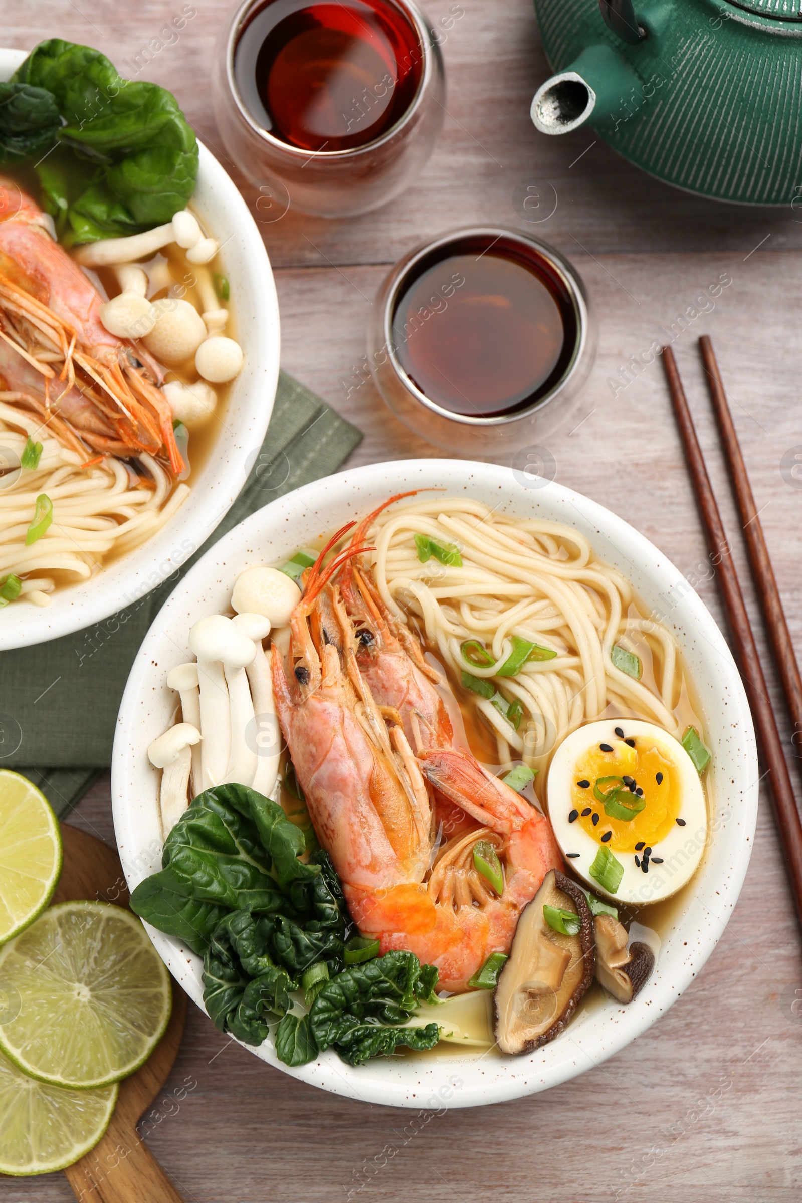 Photo of Delicious ramen with shrimps in bowls served on wooden table, flat lay. Noodle soup