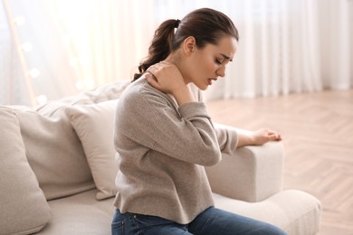 Photo of Woman suffering from neck pain at home. Bad posture problem
