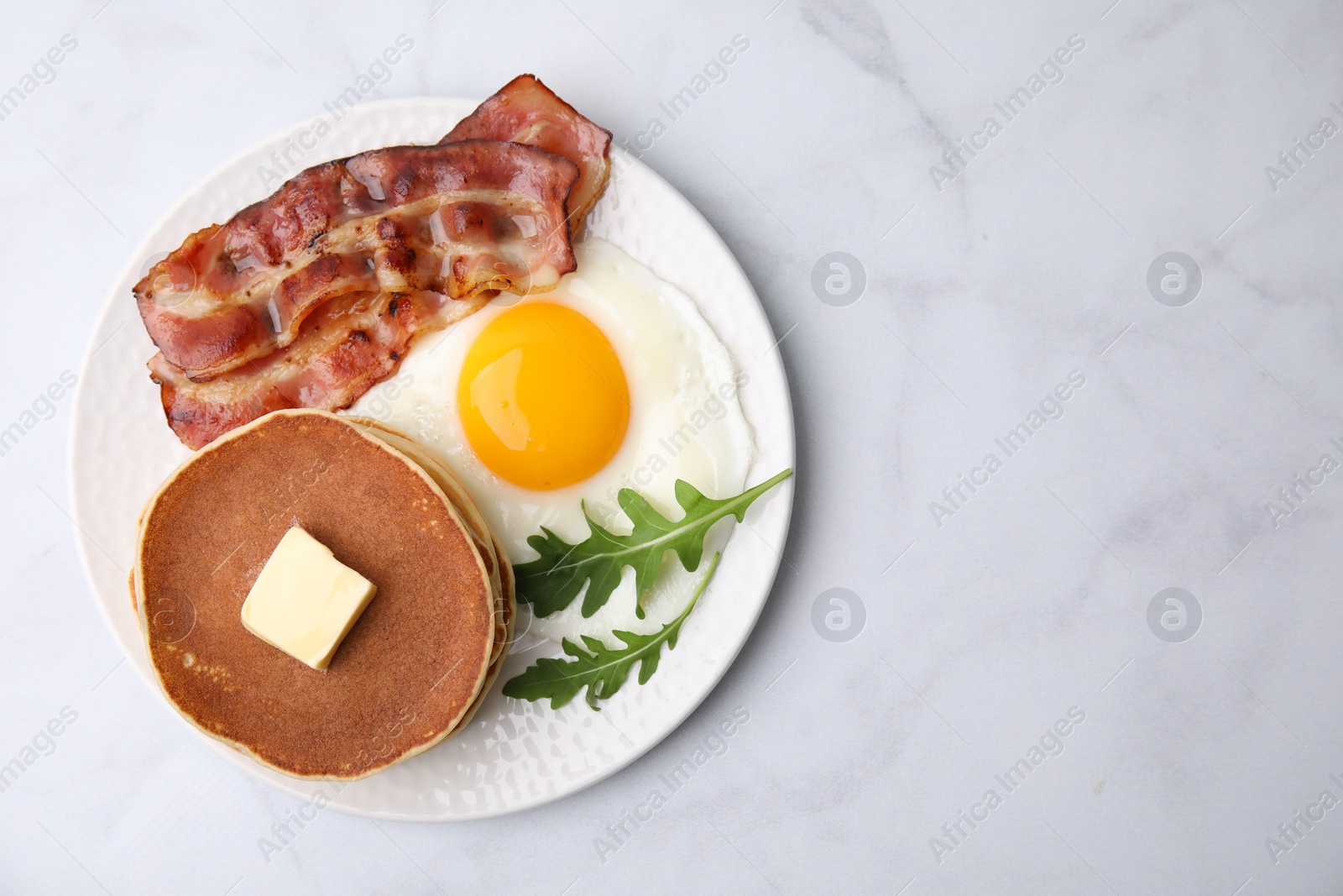 Photo of Tasty pancakes with fried egg and bacon on white table, top view. Space for text