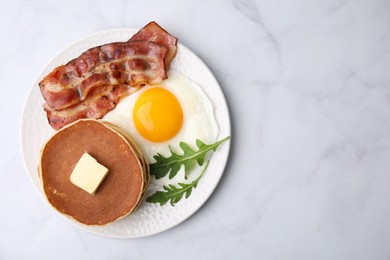 Tasty pancakes with fried egg and bacon on white table, top view. Space for text