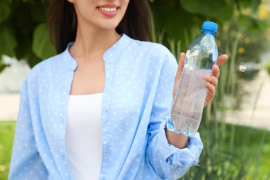 Photo of Woman with bottle of fresh water outdoors, closeup