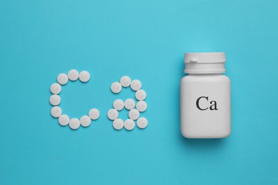 Flat lay composition with calcium supplement pills on light blue background