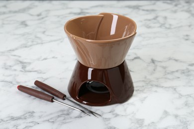 Photo of Fondue set on white marble table. Kitchen equipment