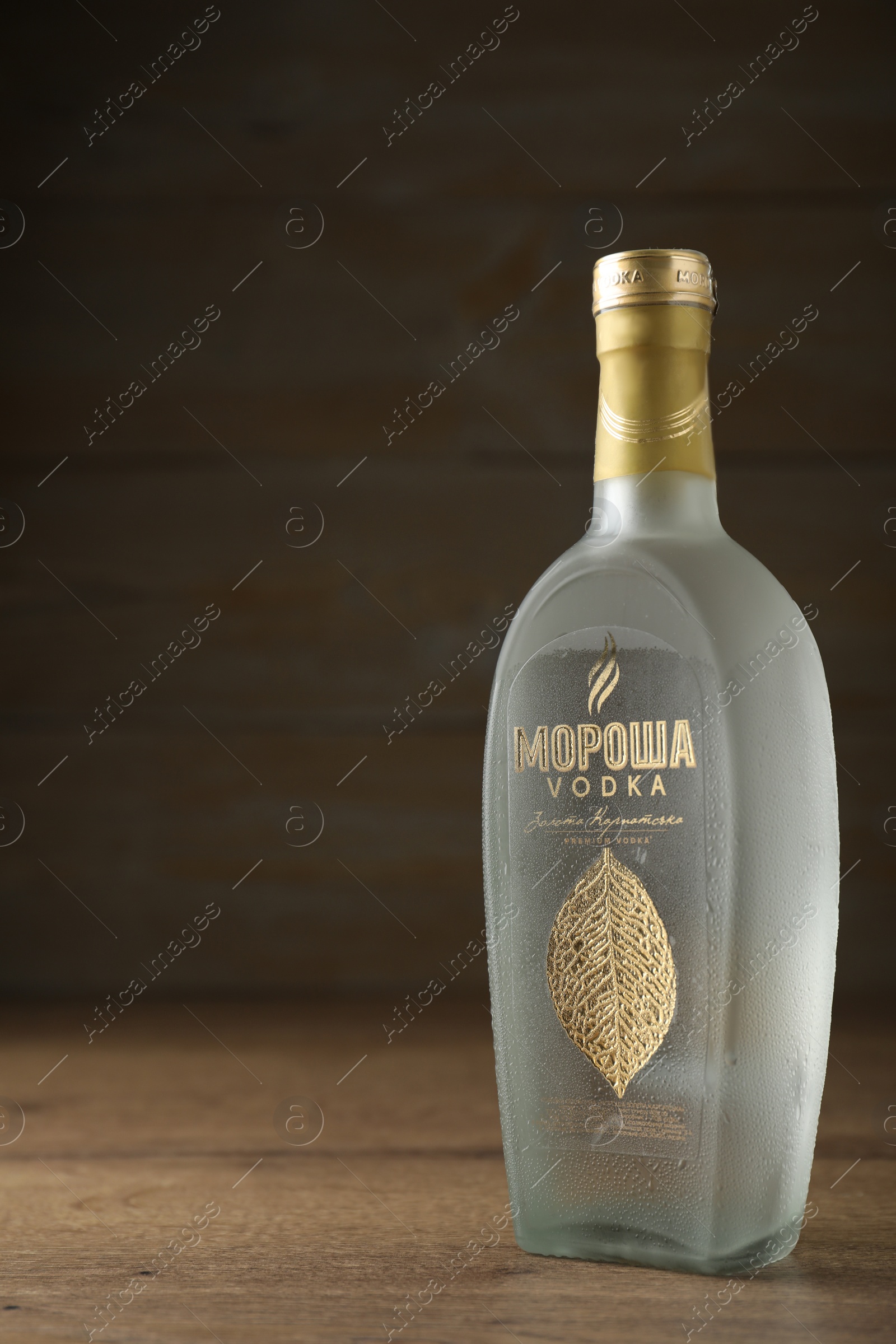 Photo of MYKOLAIV, UKRAINE - OCTOBER 03, 2019: Bottle of Morosha vodka on table against wooden background. Space for text