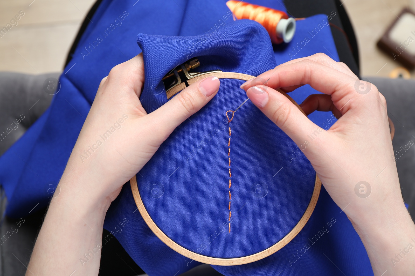 Photo of Woman with sewing needle and thread embroidering on cloth, above view
