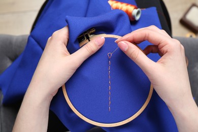 Woman with sewing needle and thread embroidering on cloth, above view