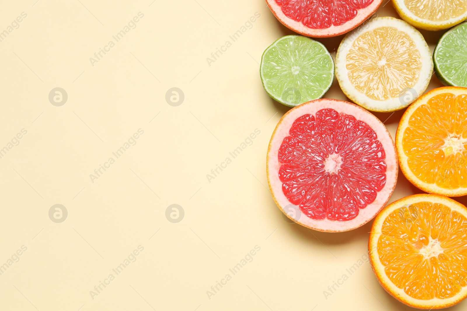 Photo of Different cut citrus fruits on beige table, flat lay. Space for text