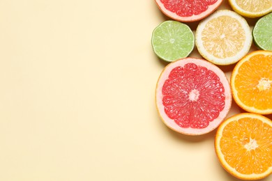 Photo of Different cut citrus fruits on beige table, flat lay. Space for text