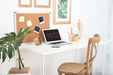 Stylish workplace with laptop on table in room