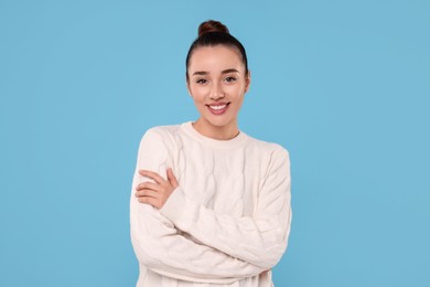 Beautiful young woman in stylish warm sweater on light blue background