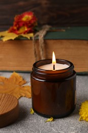 Photo of Burning scented candle on light gray textured table