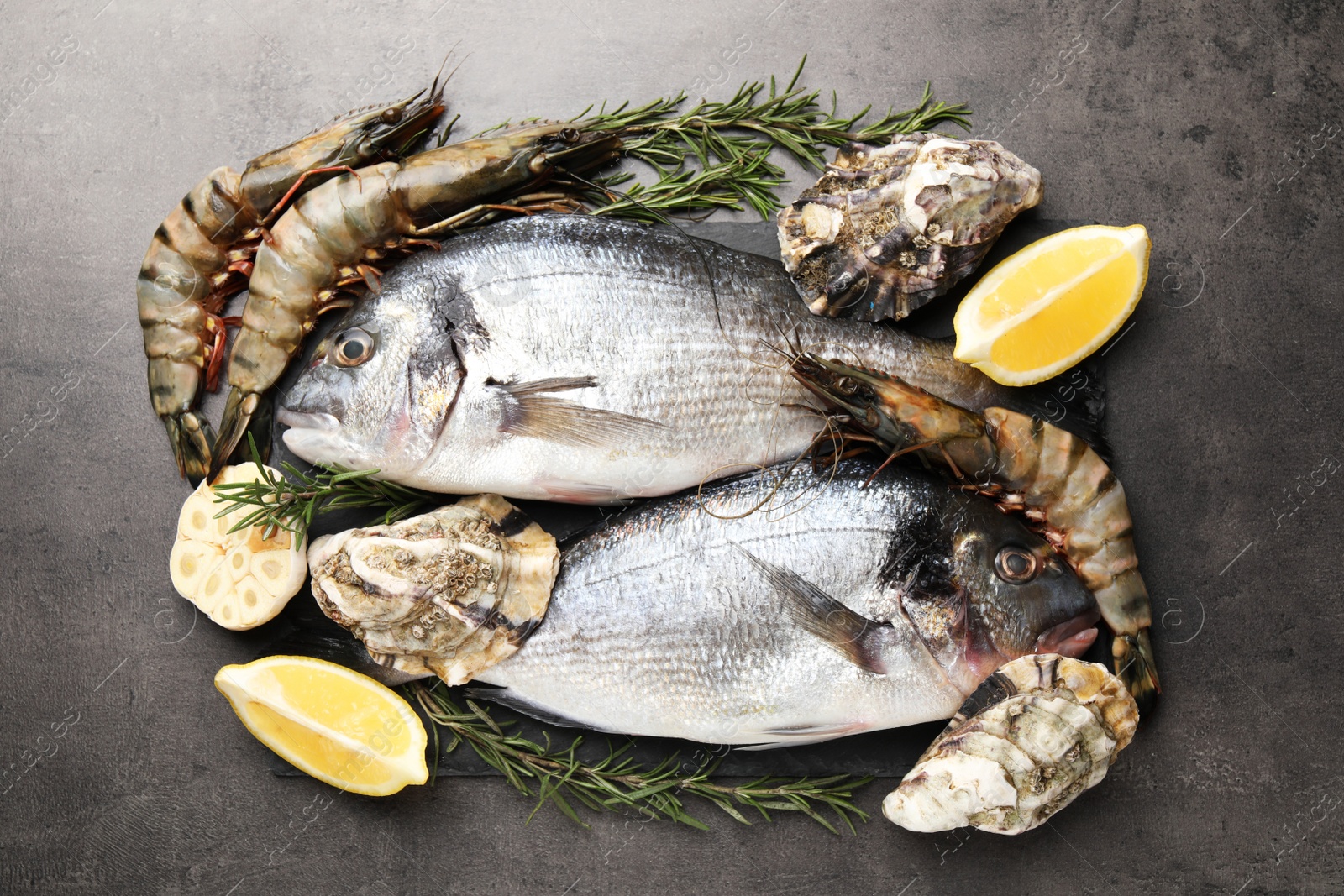 Photo of Flat lay composition with fresh raw dorado fish, shrimps and oysters on grey table