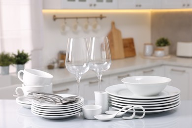 Photo of Set of clean dishware, glasses and cutlery on table in kitchen