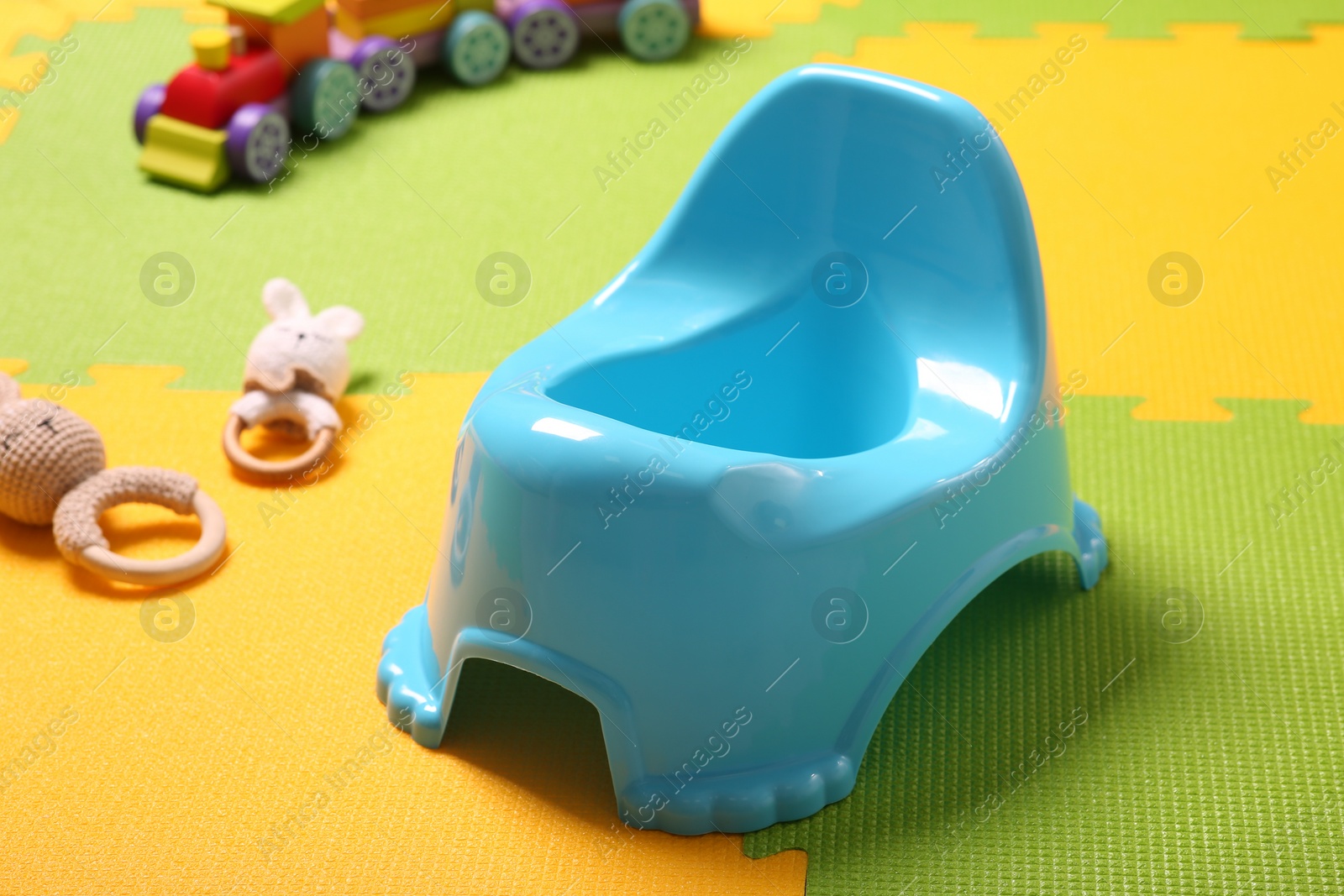 Photo of Light blue baby potty on colorful puzzle mat. Toilet training