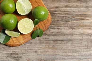 Photo of Fresh ripe limes on wooden table, top view. Space for text