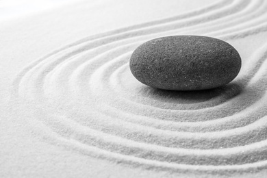 Photo of Grey stone on sand with pattern. Zen, meditation, harmony